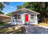 Gray house with red door, front yard, and concrete driveway at 2002 E Ellicott St, Tampa, FL 33610