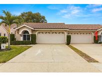 Tan two-story home with a two-car garage and manicured landscaping at 3838 Muirfield Ct, Palm Harbor, FL 34685