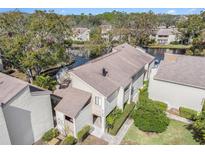 Lovely aerial view of a waterfront townhouse with mature trees and landscaping, offering a serene setting and charming curb appeal at 4154 Pinelake Ln # 101, Tampa, FL 33618