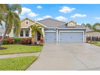 Two-story house with blue siding, three-car garage, and palm trees at 6645 Current Dr, Apollo Beach, FL 33572