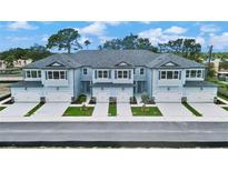 Aerial view of four townhouses with gray roofs and light blue siding, two-car garages, and landscaping at 7773 93Rd N St # 31, Seminole, FL 33777