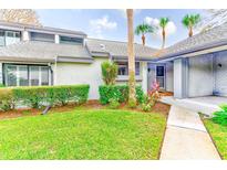 Exterior view of condo with landscaped lawn, walkway, and inviting entryway at 90 S Highland Ave # 7, Tarpon Springs, FL 34689