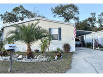 Mobile home with carport, landscaped yard, and palm trees at 10538 Bay Hills Cir, Thonotosassa, FL 33592