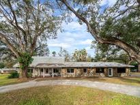 Ranch-style home with stone accents and metal roof, nestled on a spacious lot with mature trees at 1080 Buena Vista Ave, Brooksville, FL 34601