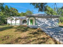 White house with green trim, attached garage, and grassy yard at 12240 Eakin St, Weeki Wachee, FL 34614