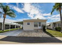 Tan single-wide manufactured home with carport and landscaped yard at 18675 Us Highway 19 N # 364, Clearwater, FL 33764