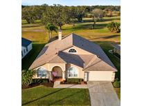 House with a tan exterior, a three-car garage, and a manicured lawn at 2102 Golf Manor Blvd, Valrico, FL 33596