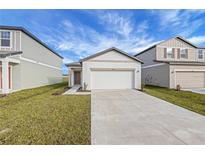 New construction home with a two-car garage and a well-manicured lawn at 35605 Buttonweed Trl, Zephyrhills, FL 33541