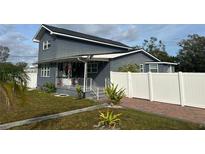 Gray house with white fence, brick driveway, and landscaping at 7336 Orchard Dr, Wesley Chapel, FL 33545