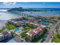 Aerial view of a waterfront community with tennis courts, pool, and lush landscaping at 845 S Gulfview Blvd # 208, Clearwater Beach, FL 33767