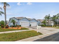 Street view of a light blue house with a two-car garage and landscaping at 11447 Golf Round Dr, New Port Richey, FL 34654