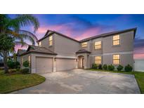 Two-story house with a three-car garage and landscaped yard at dusk at 11614 Brighton Knoll Loop, Riverview, FL 33579