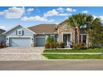 Two-story house with gray siding, stone accents, and a three-car garage at 4449 Tour Trce, Land O Lakes, FL 34638