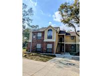 Brick condo building with stairs leading to entrance and surrounding trees at 8702 Mallard Reserve Dr # 104, Tampa, FL 33614