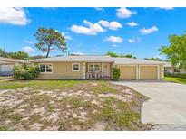 Tan single-story house with a two-car garage and mature landscaping at 1085 Indian Rocks S Rd, Largo, FL 33770