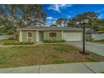 Green house with a teal door, stone accents, and a two-car garage at 12459 104Th Ter, Largo, FL 33778