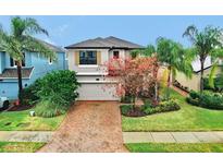 Two-story house with gray siding, brick driveway, and landscaping at 18865 Deer Tracks Loop, Lutz, FL 33558