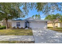 Gray house with a two-car garage and landscaped lawn at 19304 Garden Quilt Cir, Lutz, FL 33558