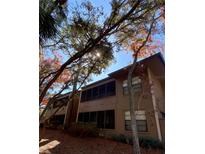 Exterior view of condo building with trees and landscaping at 204 Lennox W Rd # 204, Palm Harbor, FL 34683