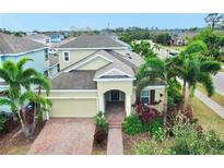 Two-story house with a light beige exterior, brick driveway, and lush landscaping at 5230 Admiral Pointe Dr, Apollo Beach, FL 33572