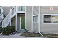 Exterior view of a light taupe condo building with green doors and stairways at 7298 Ulmerton Rd # 202, Largo, FL 33771