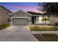 Two-story house with gray siding, two-car garage, and landscaped yard at 12152 Ledbury Commons Dr, Gibsonton, FL 33534