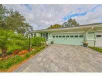 House exterior featuring a light green garage door, paved driveway, and well-manicured landscaping at 2510 Lambdin Dr, Sun City Center, FL 33573