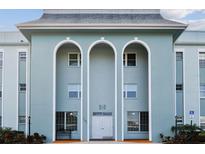 Building exterior featuring a light blue facade, three arched entryways, and landscaping at 701 Poinsettia Rd # 302, Belleair, FL 33756