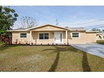 Newly renovated tan house with a white door, landscaping, and a spacious yard at 10821 Freedom Blvd, Seminole, FL 33772