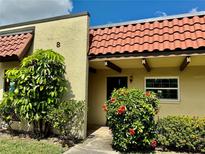 Front view of condo with lush landscaping and Spanish tile roof at 1701 Pinehurst Rd # 8B, Dunedin, FL 34698