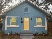 Newly renovated home with a charming light blue exterior, yellow door, and landscaping at 1751 Yale S St, St Petersburg, FL 33711