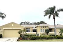 Single-story house with tan exterior, two-car garage, and palm trees at 2124 Sifield Greens Way # 11, Sun City Center, FL 33573