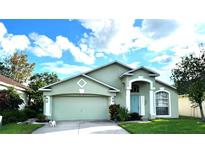 Single-story house with a green exterior, two-car garage, and landscaped lawn at 25237 Seven Rivers Cir, Land O Lakes, FL 34639