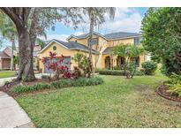 Two-story yellow house with gray garage door and lush landscaping on a spacious lot at 5608 Rockfield Loop, Valrico, FL 33596