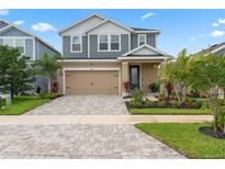 Two-story house with gray siding, tan accents, and a landscaped front yard at 5636 Silver Sun Dr, Apollo Beach, FL 33572