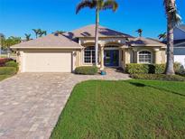 Beautiful single-story home with a lush green lawn, a brick driveway, and a two-car garage at 924 Landmark S Cir, St Petersburg, FL 33715