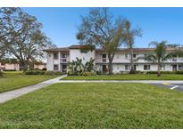 Inviting two-story condo with balconies, mature trees, and a well-maintained green lawn at 130 Lakeview Way # 130, Oldsmar, FL 34677