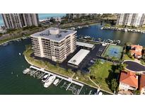 Aerial view of waterfront condo building with tennis court, parking, and boat slips at 1651 Sand Key Estates Ct # 84, Clearwater Beach, FL 33767