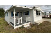 White mobile home with blue accents, covered porch, and landscaped yard at 1710 7Th Sw St # 83, Ruskin, FL 33570