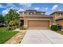Two-story house with tan exterior, attached garage, and landscaped lawn at 17443 Glenapp Dr, Land O Lakes, FL 34638