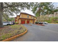 Tan two-story condo building with attached garages and lush landscaping at 2160 Chianti Pl # 11-0117, Palm Harbor, FL 34683