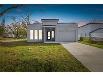 Modern single-story home with gray exterior, stone accents, and attached garage at 7711 N Orleans Ave, Tampa, FL 33604