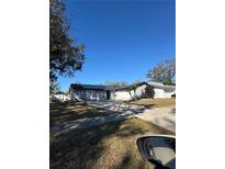 Ranch-style home with gray siding, solar panels, and a driveway at 15906 Country Farm Pl, Tampa, FL 33624
