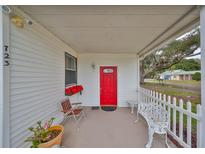 Inviting front porch with red door, white picket fence, and comfortable seating at 723 Ornelda Sw St, Ruskin, FL 33570