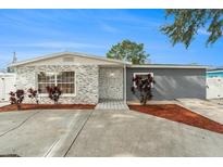 Remodeled home with gray and stone exterior, landscaping, and driveway at 5118 Murray Hill Dr, Tampa, FL 33615