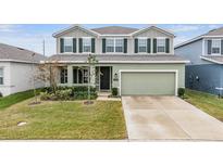 Two-story house with green exterior, two-car garage, and landscaped lawn at 7878 Greenway Ave, Wesley Chapel, FL 33544