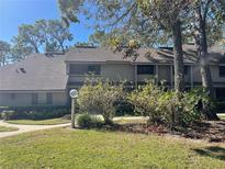 Two-story condo building with a shingled roof, surrounded by lush landscaping at 103 Old Mill Pond Rd, Palm Harbor, FL 34683