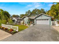 Charming light blue house with white picket fence, landscaping, and a two-car garage at 1030 Charles St, Clearwater, FL 33755