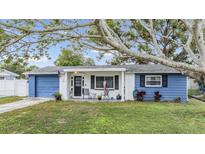 Charming ranch home with blue exterior, covered porch, and well-maintained lawn at 3303 Bainbridge Dr, Holiday, FL 34691