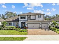 Two-story home with gray and white exterior, three-car garage, and landscaped yard at 821 Forest Glen Ct, Palm Harbor, FL 34683